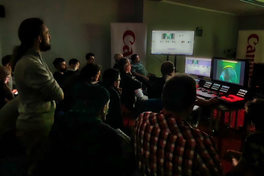 Grupa studentów obserwuje pracę na stanowisku edycji filmowej i koloryzacji