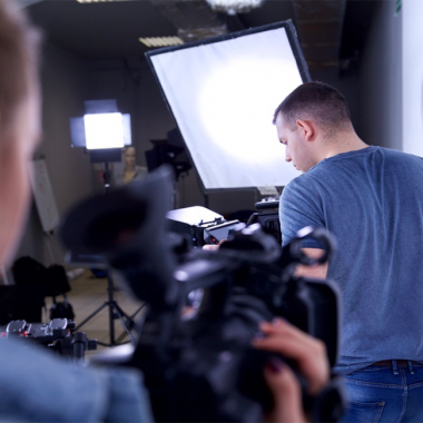 Film production studio with lighting equipment and cameraman during shooting