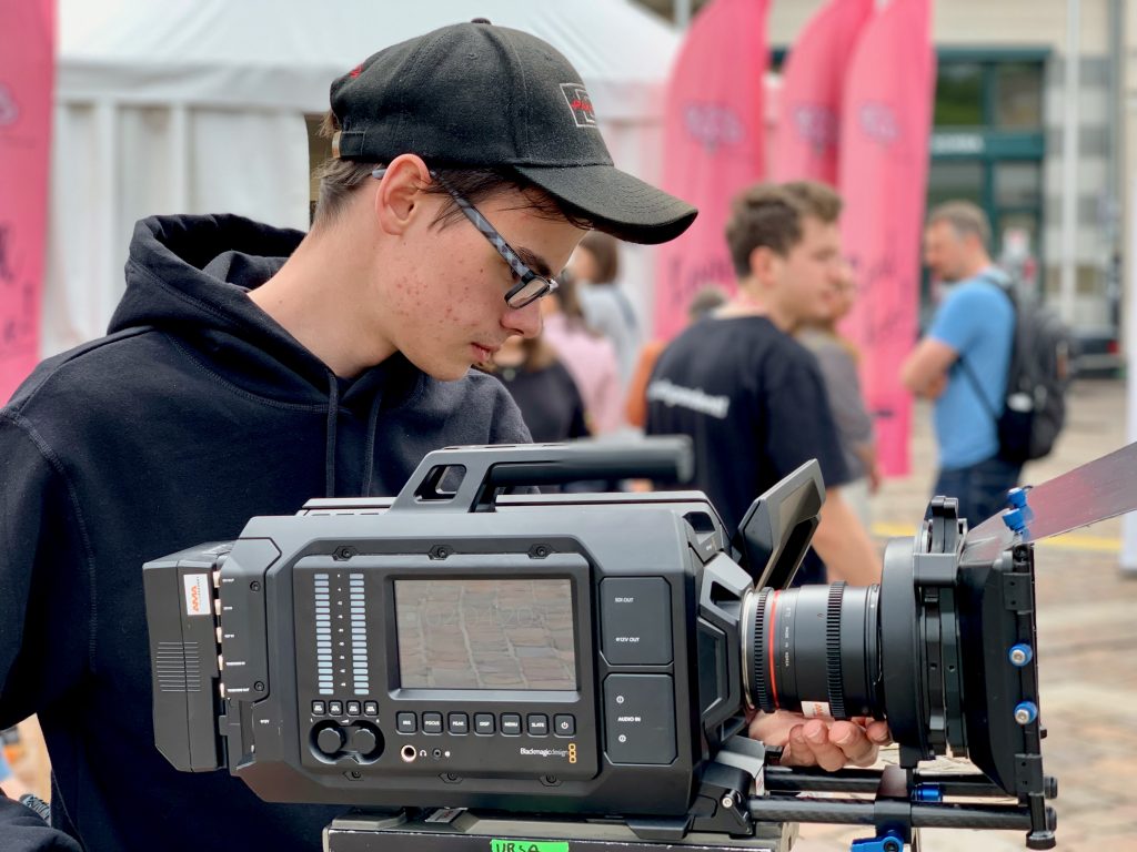 Młody filmowiec obsługuje profesjonalny sprzęt kamerowy na terenie szkoły