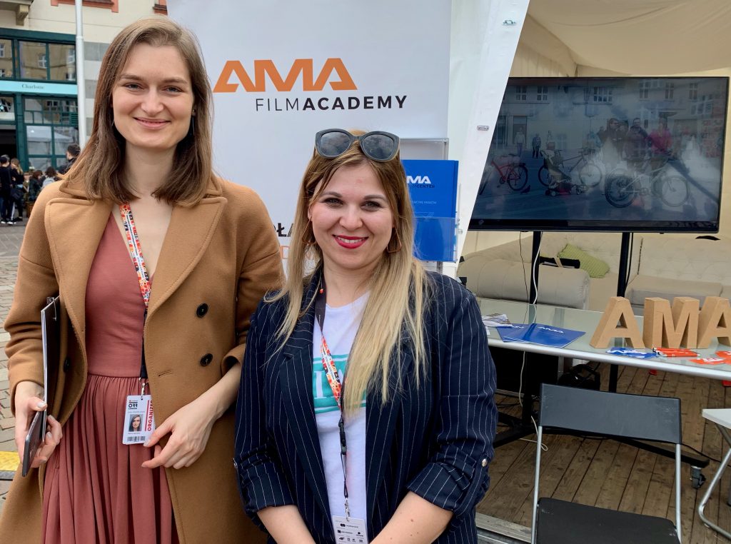 Dwie kobiety pozują przed logiem AMA Film Academy w studiu produkcji