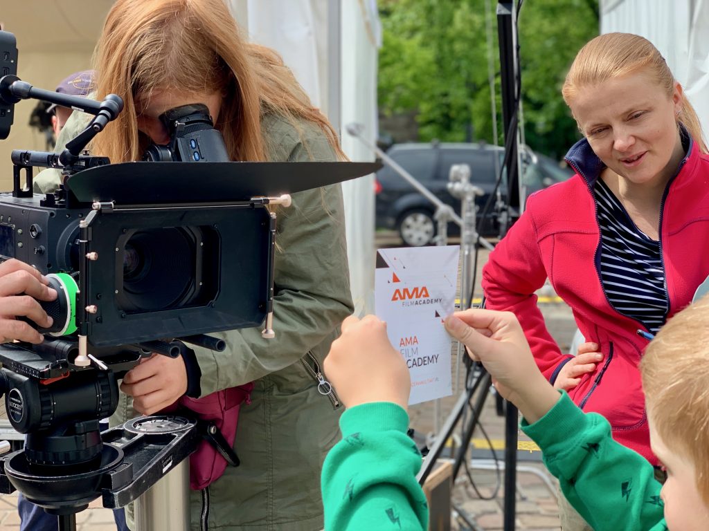 Kamerzysta i kobieta w czerwonej kurtce pracują przy kamerze filmowej outdoorowo