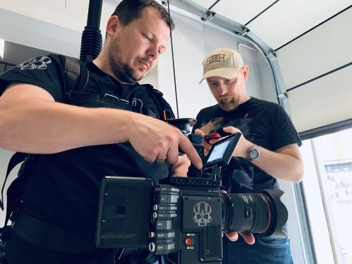 Dwaj mężczyźni pracują z profesjonalną kamerą filmową w jasnym studiu