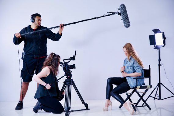 Profesjonalna ekipa filmowa nagrywa wywiad z kobietą na białym tle studia