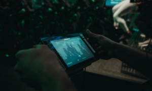 Ręka trzymająca tablet z niebieskim ekranem w ciemnym otoczeniu
