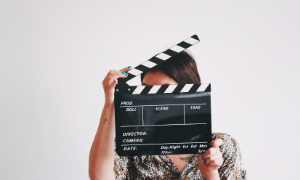 Osoba trzymająca klasyczną klaps filmową na białym tle studyjnym