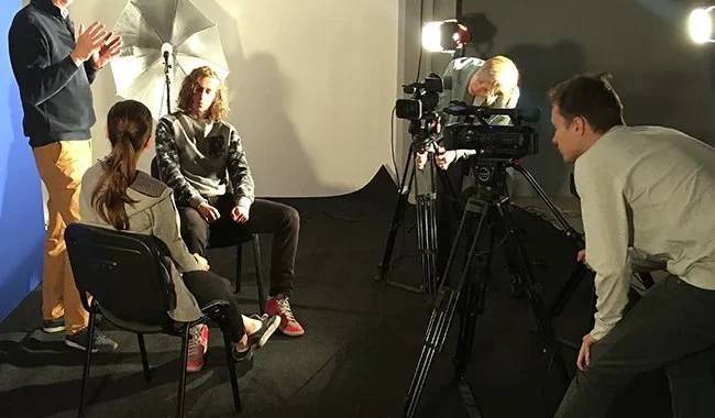 Studenci szkoły filmowej pracują przy kamerze podczas nagrań na planie filmowym