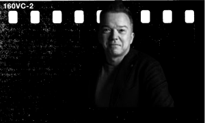 Portret czarno-białego zdjęcia mężczyzny w ciemnej odzieży na tle filmowej taśmy