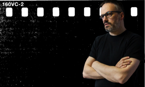 Jarosław Barzan, mężczyzna w czarnej koszulce, portret na tle filmowej klatki
