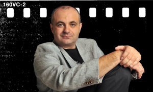 Portret mężczyzny w szarej marynarce siedzi na tle filmowego negatywu