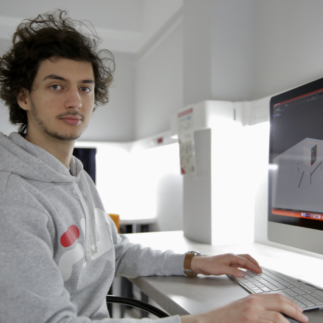 Młody mężczyzna przy komputerze pracuje nad projektem filmowym w studiu