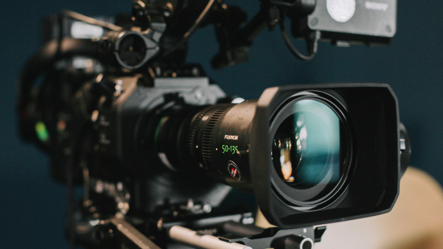 Profesjonalny sprzęt filmowy z kamerą i obiektywem na niebieskim tle