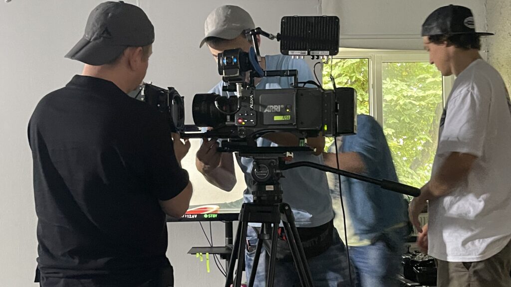 Trzaj mężczyzni pracują przy profesjonalnym sprzęcie filmowym podczas zajęć