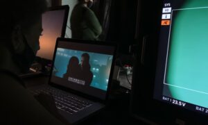 Studio postprodukcji z monitorami, laptopem i studentem pracującym nad edycją wideo