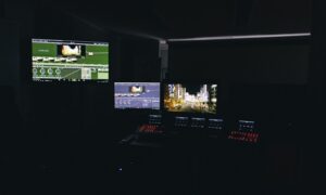 Stanowisko pracy postprodukcji z wieloma monitorami i sprzętem edycyjnym w ciemnym studiu