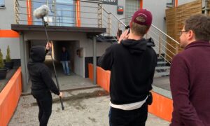 Studenci podczas ćwiczeń praktycznych z realizacji dźwięku przed budynkiem akademii