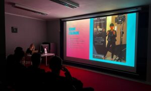 Prezentacja szkoły filmowej z projekcją na dużym ekranie i widzami w sali