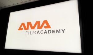 Logo AMA Film Academy wyświetlane na białym ekranie projekcyjnym w ciemnej sali