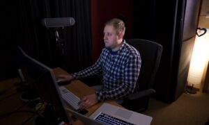 Mężczyzna pracujący przy stanowisku audio z mikrofonem i komputerem