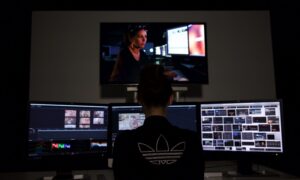 Student przy stanowisku do edycji wideo z trzema monitorami i zawartością projektu