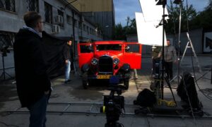 Plac filmowy ze starym czerwonym samochodem i sprzętem oświetleniowym do produkcji