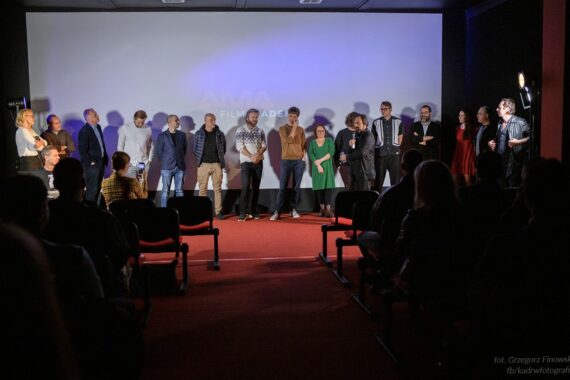 Grupa ludzi stoi na czerwonej scenie podczas inauguracji AMA Film Academy