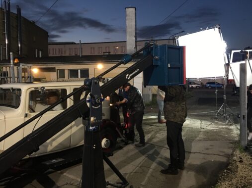 Ekipa filmowa przy sprzęcie oświetleniowym na planie zdjęciowym o zmroku