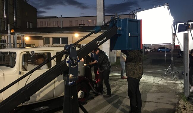 Ekipa filmowa przy sprzęcie oświetleniowym na planie zdjęciowym o zmroku
