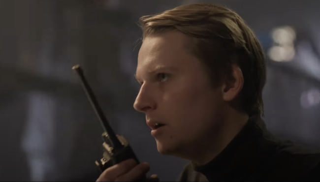 Mężczyzna w profilu trzymający pistolet, scena z filmu akcji
