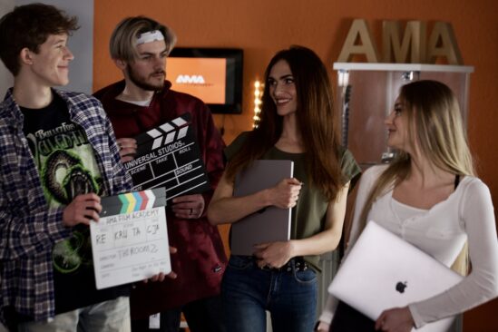 Czterej studenci AMA Film Academy na planie filmowym z klapą produkcyjną