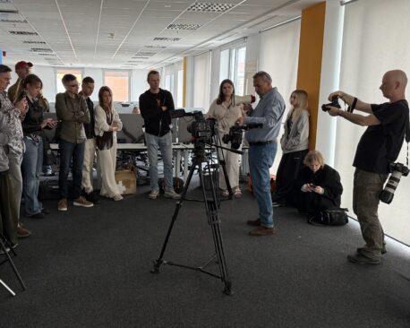 Grupa studentów obserwuje profesjonalny sprzęt filmowy podczas zajęć na dniu otwartym